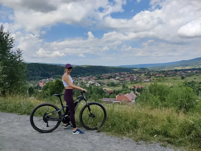 Cyclist with an e-bike on a gravel track overlooking a village near Sovata